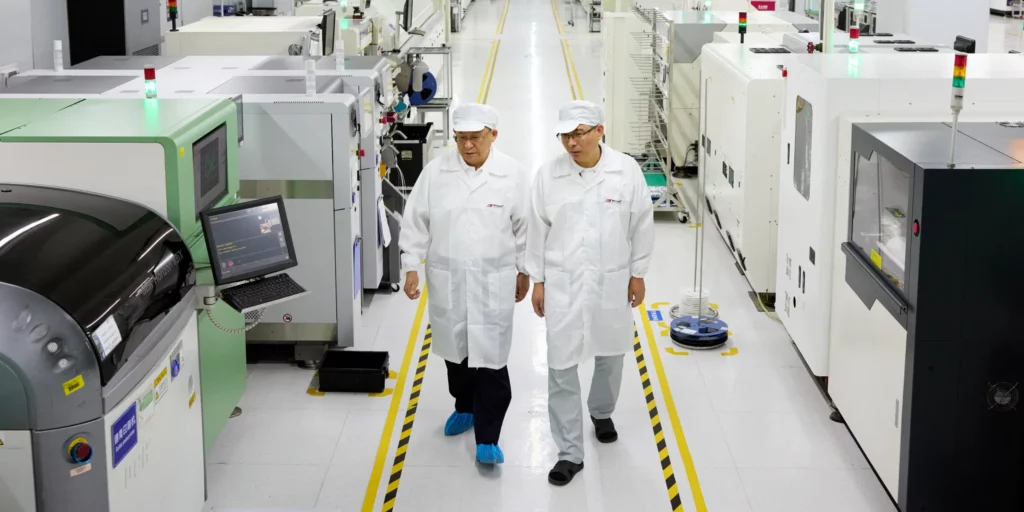 Two Ryder Industries engineers in white lab coats inspecting SMT production lines.