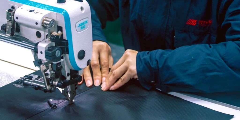 Close-up of hands guiding material under a sewing machine.